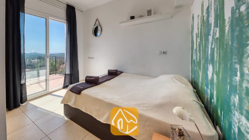 Villas de vacances Costa Brava Espagne - Villa Sofia - Chambre avec un lit double, un mur d'accent peint en blanc et vert, et une porte-fenêtre coulissant donnant sur un balcon extérieur.