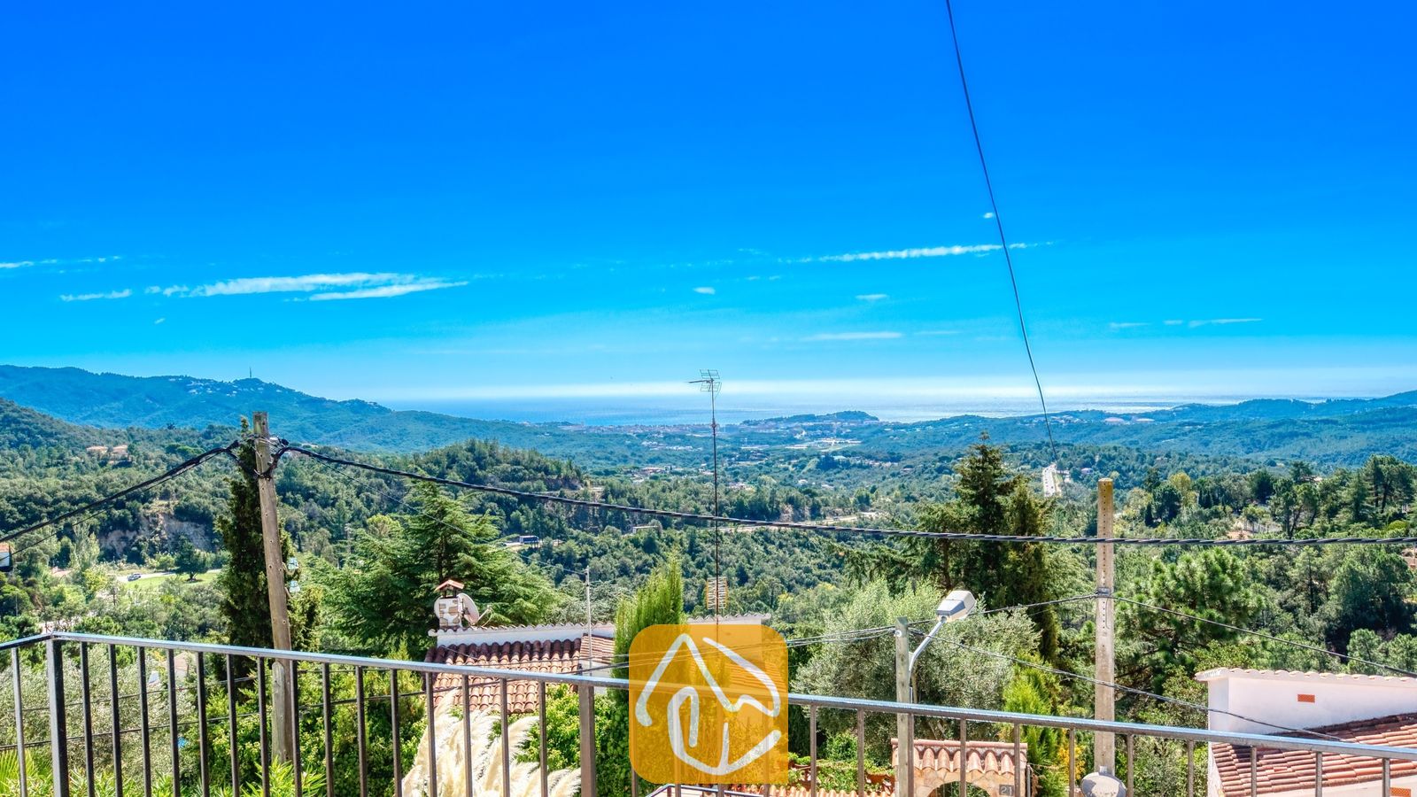 Vakantievilla's Costa Brava Spanje - Villa Sofia - Uitzicht vanaf het balkon van Villa Sofia op de groene heuvels, boomtoppen en de verre zee onder een helderblauwe hemel