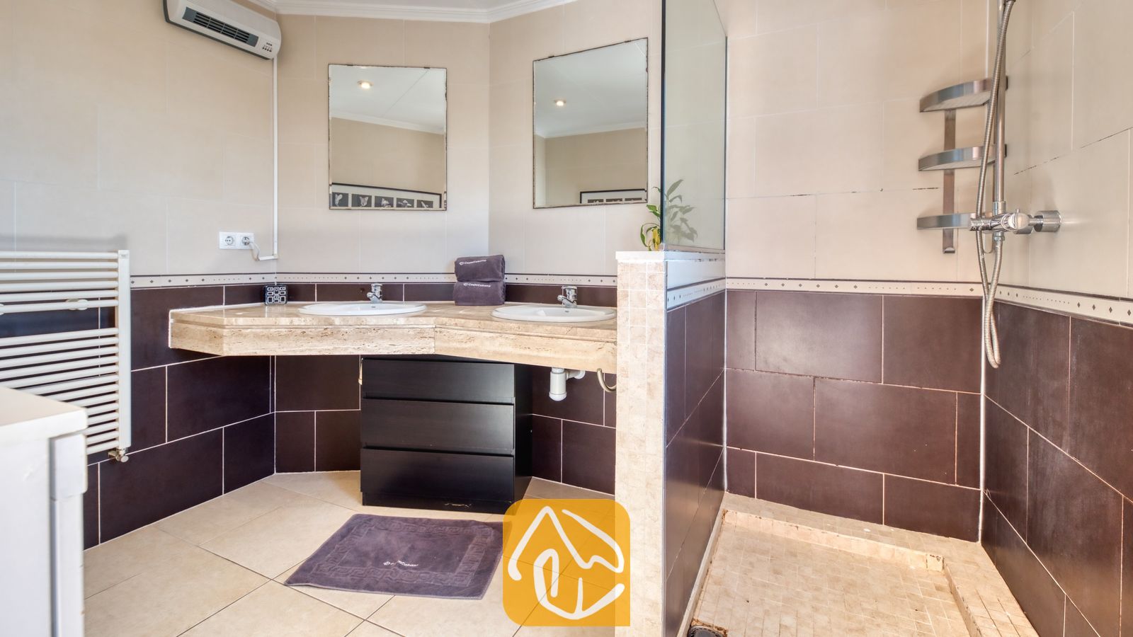 Vakantievilla's Costa Brava Spanje - Villa Sofia - Badkamer met een dubbele wastafel, een marmeren aanrechtblad, twee rechthoekige spiegels en een open inloopdouche met metalen planken.