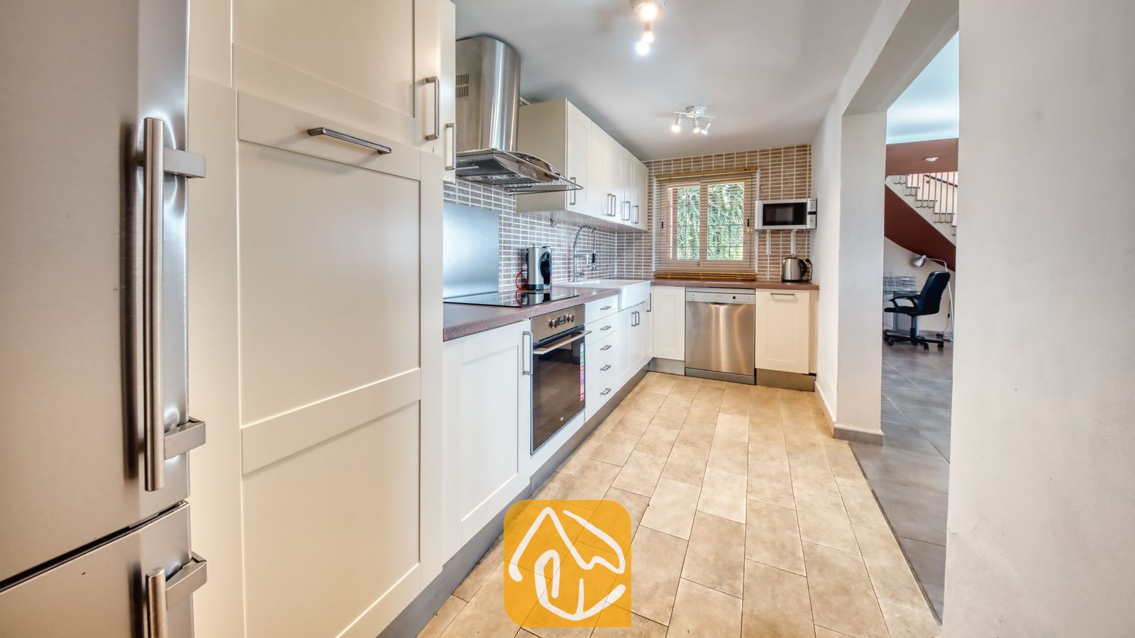 Vakantievilla's Costa Brava Spanje - Villa Sofia - Moderne keuken met witte kasten, roestvrijstalen apparatuur en een betegelde achterwand in Villa Sofia.