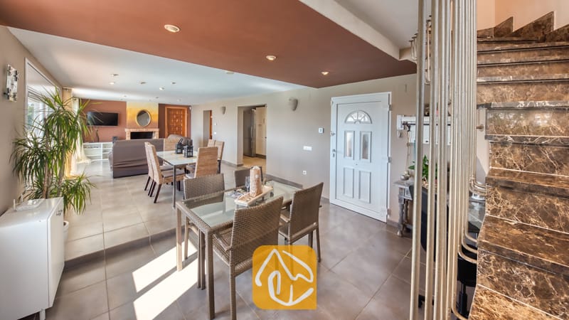 Vakantievilla's Costa Brava Spanje - Villa Sofia - Het ruime interieur van Villa Sofia, met een marmeren trap, twee glazen eettafels met gevlochten stoelen en een zitgedeelte op de achtergrond.