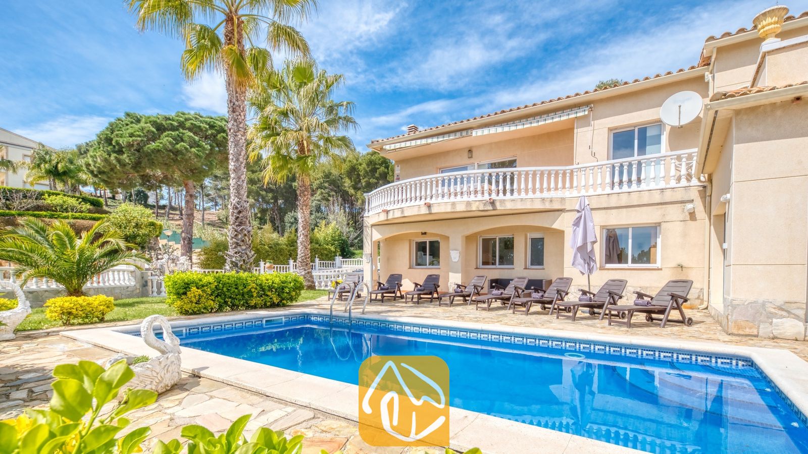 Vakantievilla's Costa Brava Spanje - Villa Estrella - Privé buitenzwembad bij Villa Estrella met helderblauw water, ligstoelen en palmbomen tegen een blauwe lucht.
