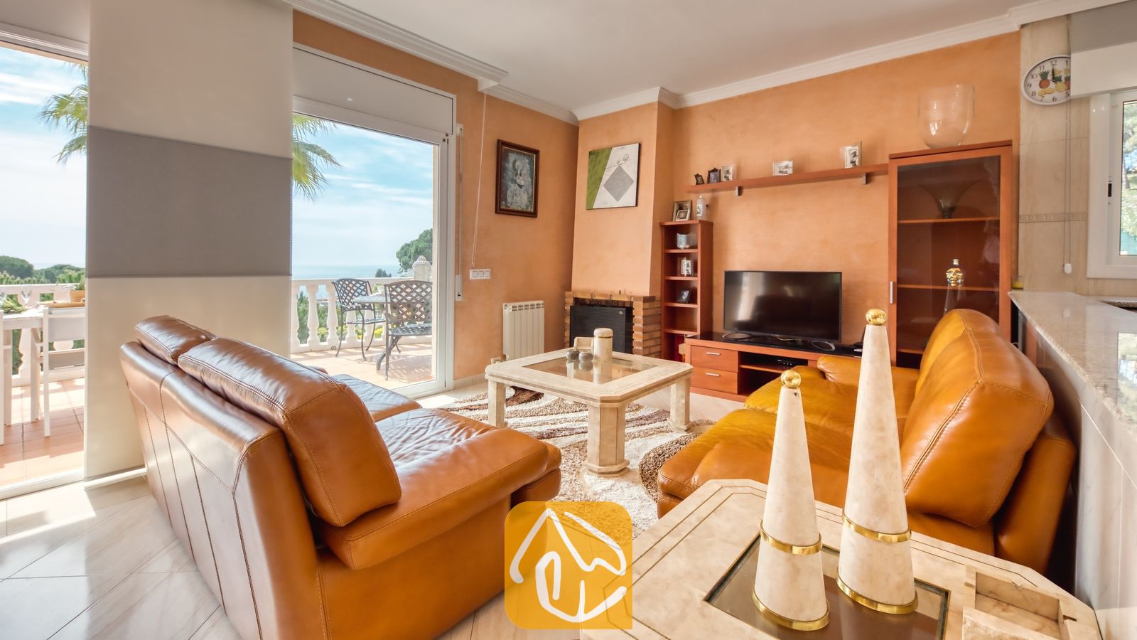 Vakantievilla's Costa Brava Spanje - Villa Estrella - Woonkamer van Villa Estrella met twee bruine lederen banken, een salontafel met glazen blad en schuifpui die toegang biedt tot een terras met uitzicht op zee.