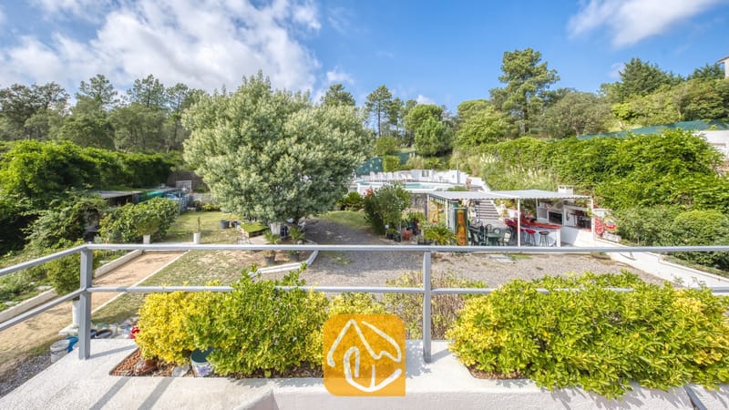 Villas de vacances Costa Brava Espagne - Villa Geolouk - Vue d'ensemble du jardin luxuriant et du bar extérieur de la Villa Geolouk, pris depuis un balcon avec des arbustes verts en pot sur fond d'arbres et d'un ciel bleu.