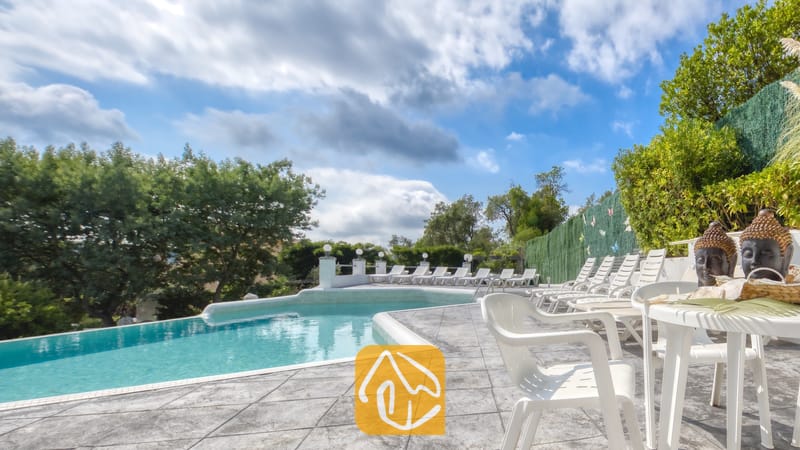 Vakantievilla's Costa Brava Spanje - Villa Geolouk - Privézwembad met betegeld terras en witte kunststof ligstoelen bij Villa Geolouk onder een licht bewolkte hemel.