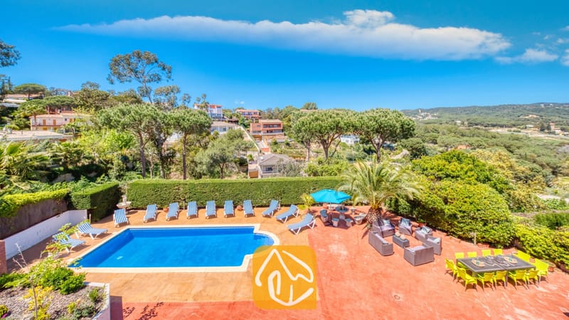Vakantievilla's Costa Brava Spanje - Villa Jaruco - Privé-buitenzwembad bij Villa Jaruco, voorzien van een terracotta terras met blauw-witte gestreepte ligbedden en een eethoek onder een blauwe hemel.