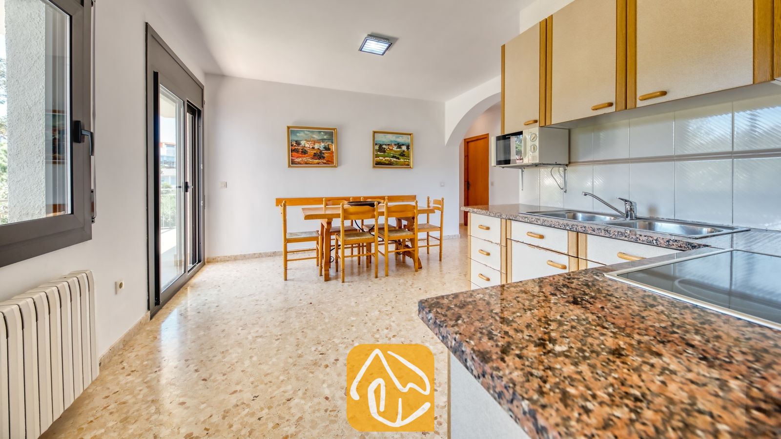 Vakantievilla's Costa Brava Spanje - Villa Jaruco - De keuken en eethoek van Villa Jaruco, voorzien van granieten aanrechtbladen, houten kasten en een eettafel met zes stoelen.