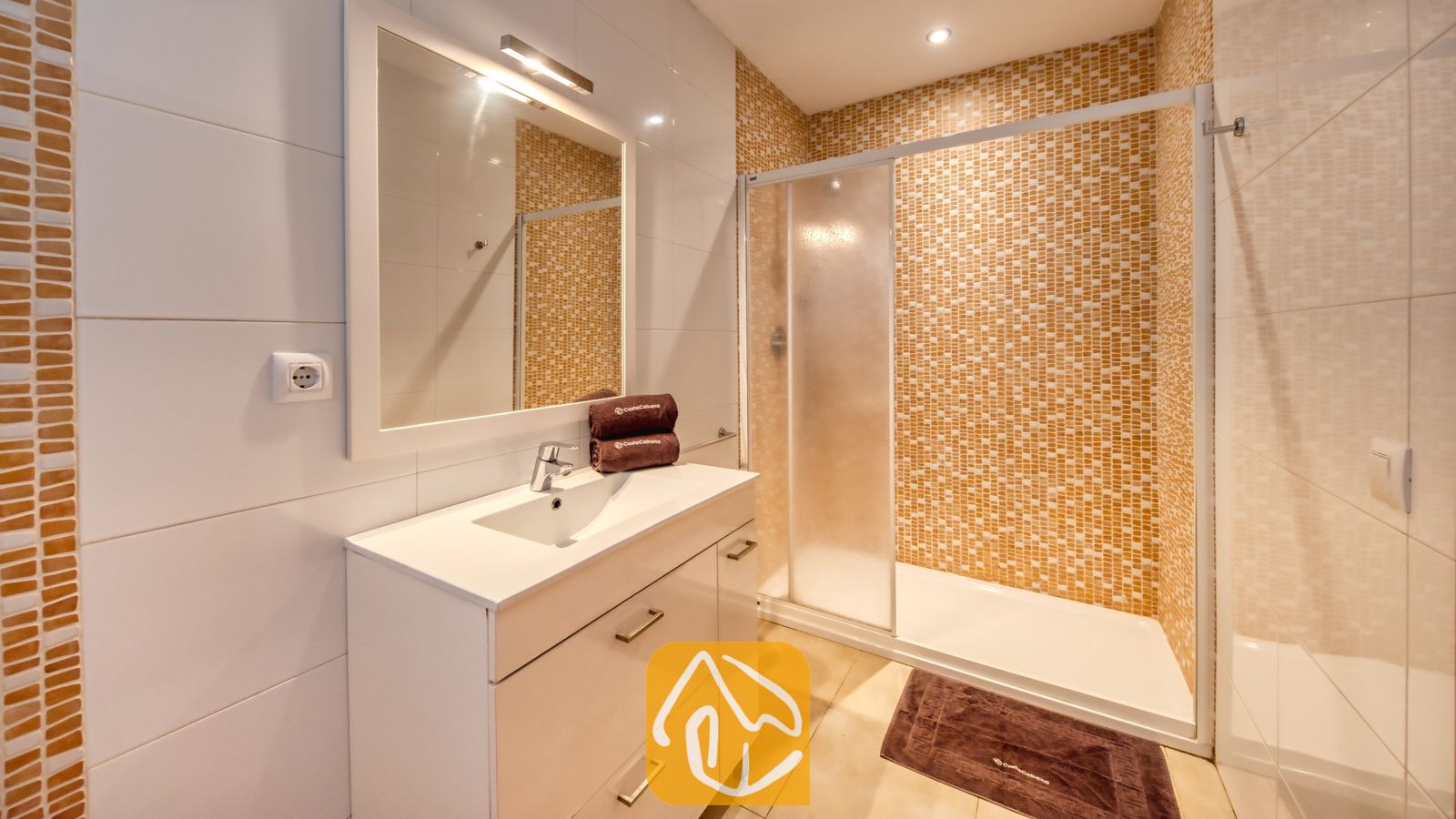 Vakantievilla's Costa Brava Spanje - Villa Lloret - Moderne badkamer met een wit wastafelmeubel met lades, een rechthoekige spiegel en een inloopdouche met oranje mozaïektegels.