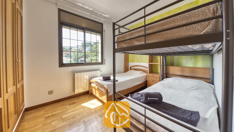 Villas de vacances Costa Brava Espagne - Villa Paris - Chambre avec lit superposé en métal foncé, parquet en bois, lit simple en bois et fenêtre donnant sur la verdure.