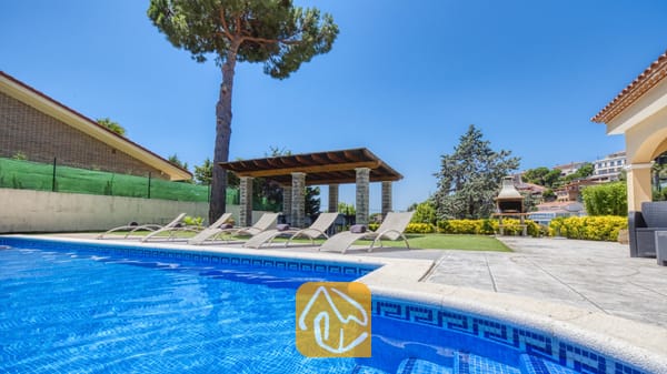 Vakantievilla's Costa Brava Spanje - Villa Paris - Privé-buitenzwembad bij Villa Paris met blauw getegelde randen, diverse ligstoelen op het terras, een overdekte pergola en een stenen barbecue op de achtergrond.