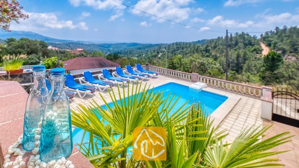 Vakantievilla's Costa Brava Spanje - Villa Santa Maria - Privé buitenzwembad bij Villa Santa Maria met blauwe ligstoelen op het tegelterras en groene heuvels in de verte
