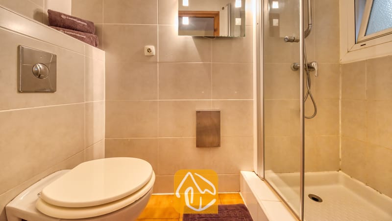 Villas de vacances Costa Brava Espagne - Villa Santa Maria - Salle de bains moderne dotée de carreaux de mur en céramique beige, de toilettes blanches et d'une douche à l'italienne vitrée avec robinetterie chromée.