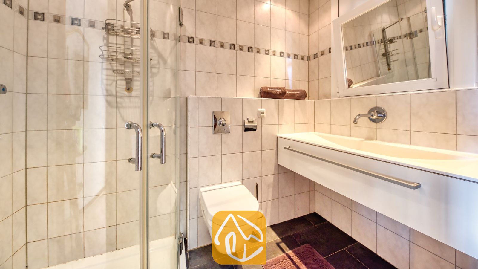 Vakantievilla's Costa Brava Spanje - Villa Santa Maria - Moderne badkamer met een glazen inloopdouche, een hangend toilet en een wit zwevend badkamermeubel met een bijbehorende spiegel.