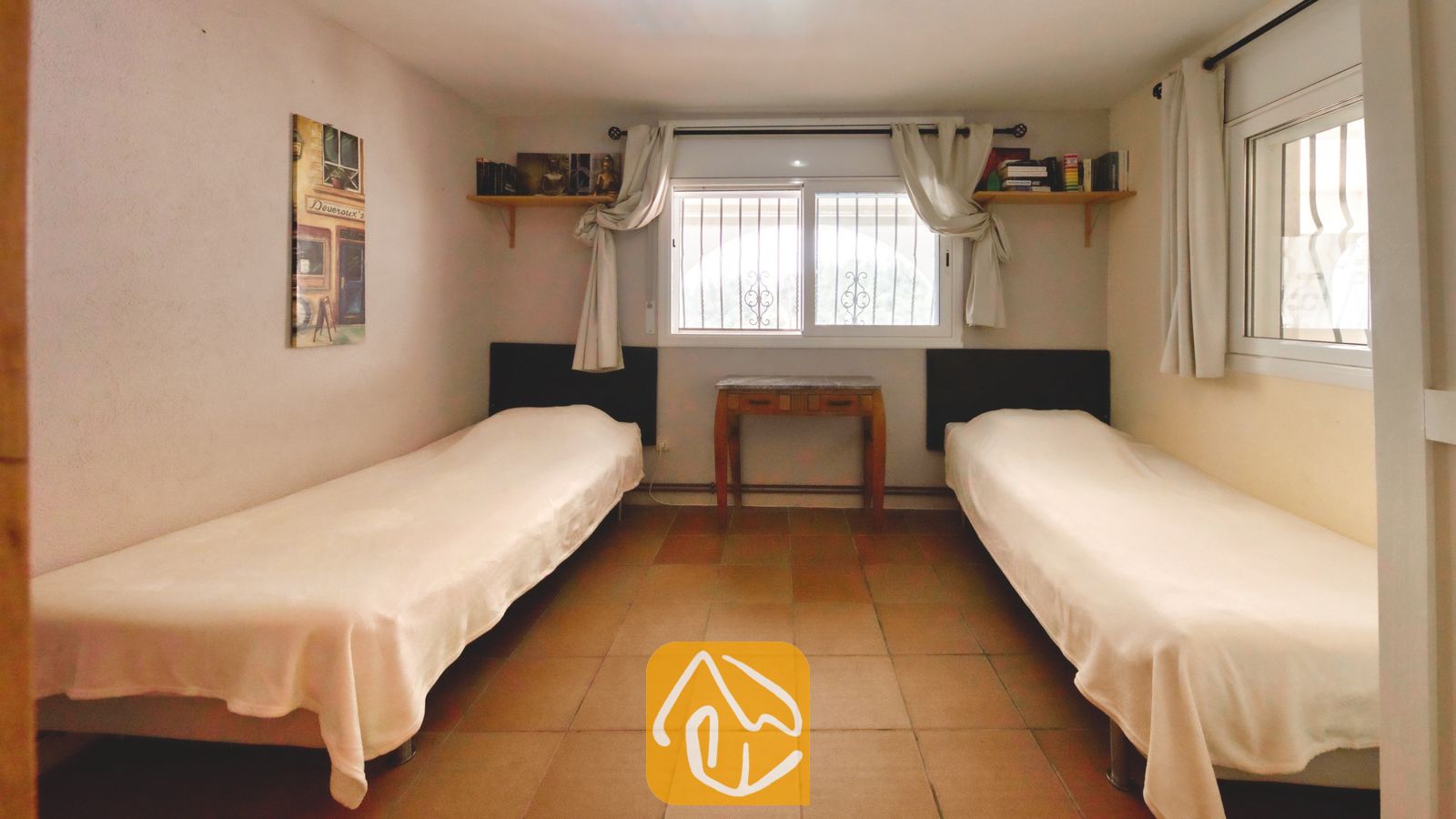 Vakantievilla's Costa Brava Spanje - Villa Santa Maria - Slaapkamer met twee eenpersoonsbedden, tegelvloeren, witte gordijnen en wandboekenplanken.