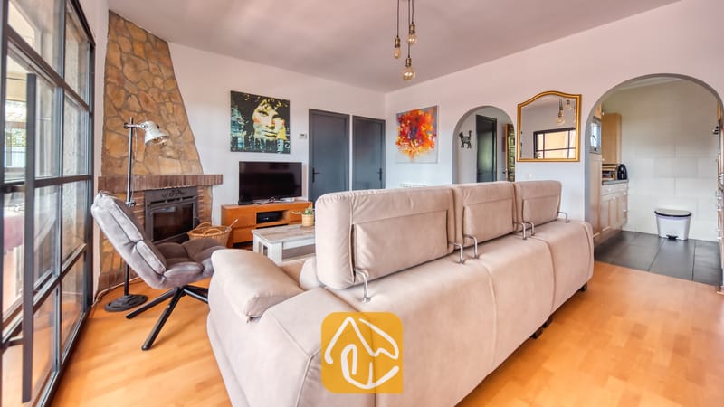 Vakantievilla's Costa Brava Spanje - Villa Santa Maria - Ruime woonkamer in Villa Santa Maria met een grote beige bank, een stenen open haard en een televisie.