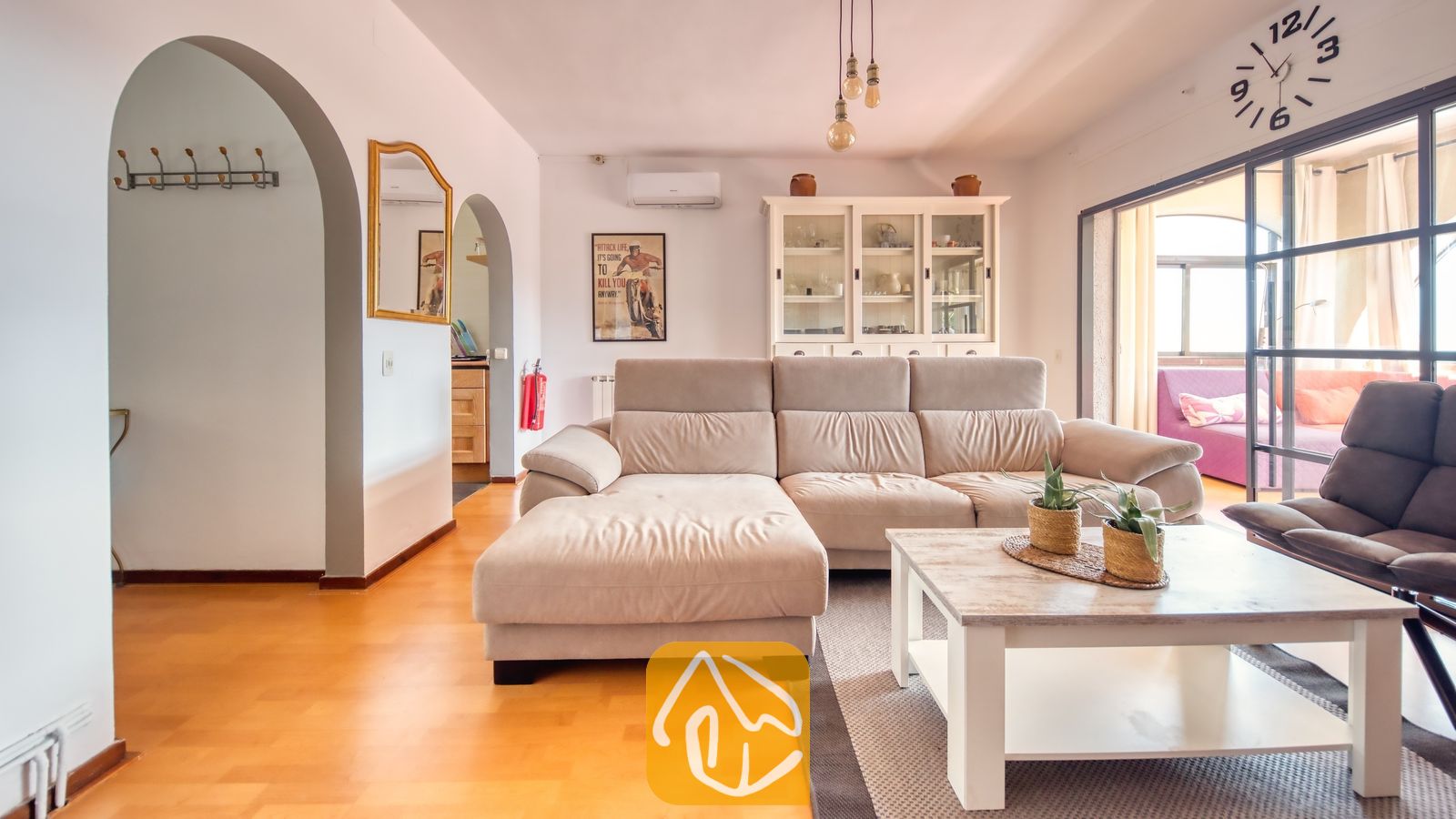 Vakantievilla's Costa Brava Spanje - Villa Santa Maria - Interieur van de woonkamer met een beige hoekbank, een witte houten salontafel met potplanten en bogen als doorgangen bij Villa Santa Maria.