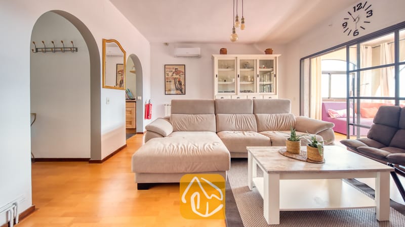 Vakantievilla's Costa Brava Spanje - Villa Santa Maria - Interieur van de woonkamer met een beige hoekbank, een witte houten salontafel met potplanten en bogen als doorgangen bij Villa Santa Maria.