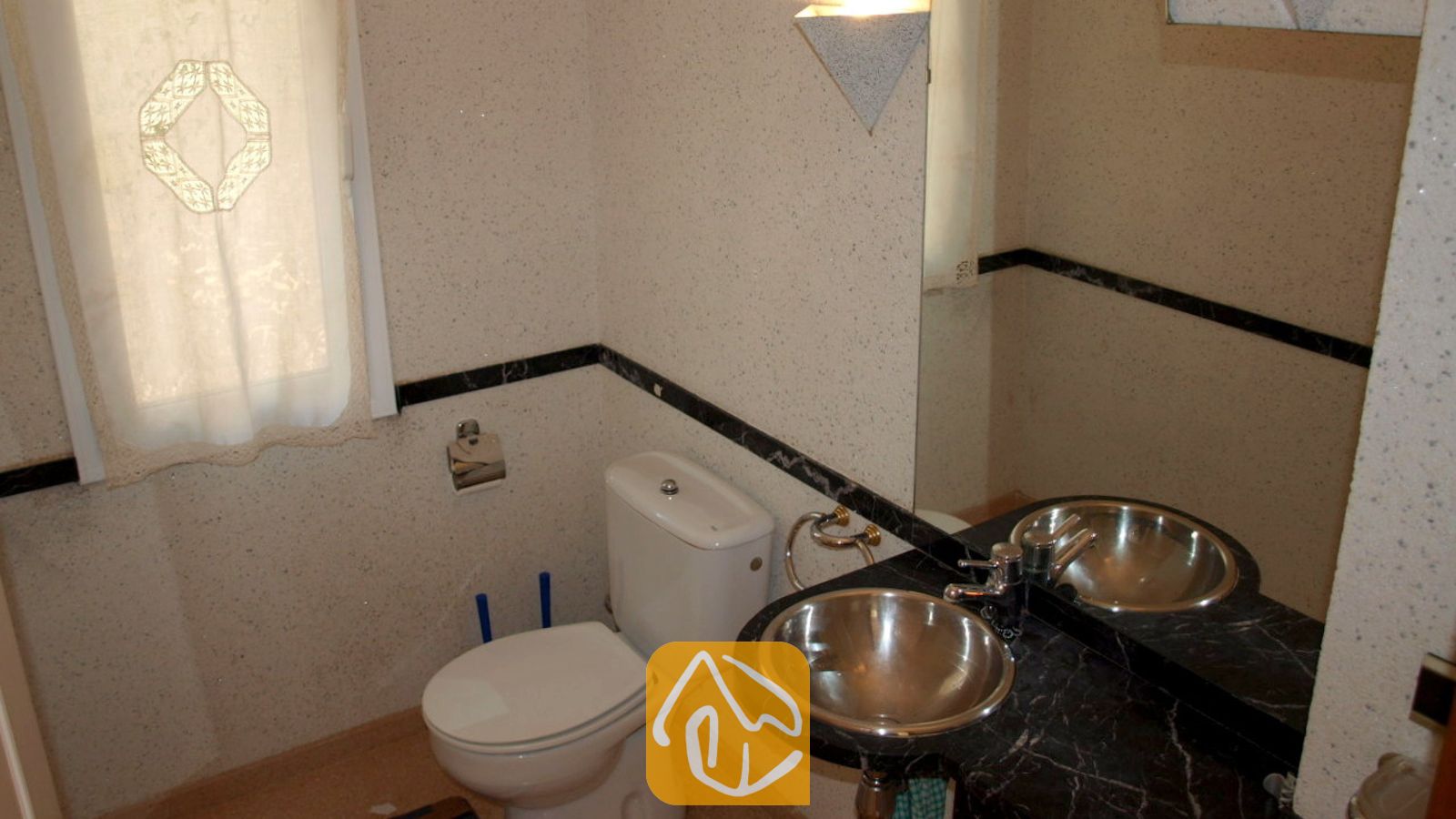 Vakantievilla's Costa Brava Spanje - Villa Valentina - Compacte badkamer met een wit toilet, een zwart marmeren wastafelblad met een ronde metalen waskom, en een matglasraam met een gedessineerd gordijn.