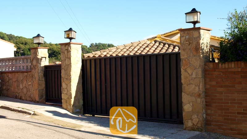 Villas de vacances Costa Brava Espagne - Villa Valentina - Portail d'allée en métal sombre encadré de piliers en pierre dotés de lampes d'extérieur à l'entrée de la Villa Valentina en Espagne