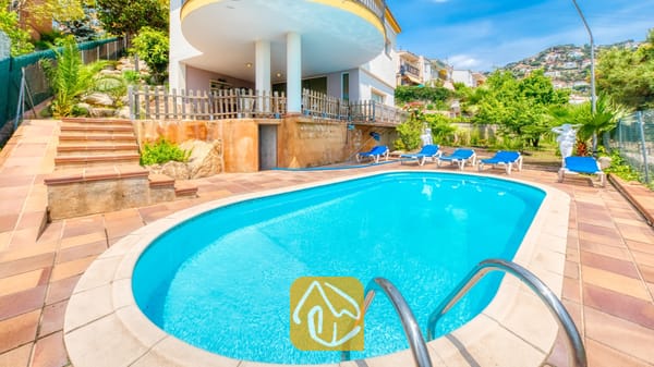 Vakantievilla's Costa Brava Spanje - Villa Valentina - Zwembad met een ovale vorm en helderblauw water bij Villa Valentina in Spanje, omringd door een betegeld terras, blauwe ligbedden, stenen treden en tuinarchitectuur.