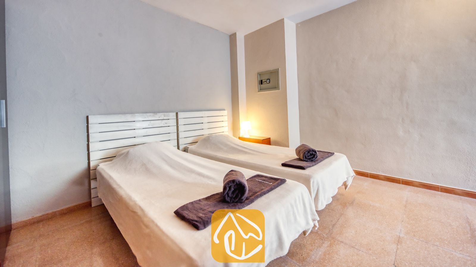 Vakantievilla's Costa Brava Spanje - Villa Valentina - Slaapkamer met twee eenpersoonsbedden, voorzien van witte houten hoofdborden, wit beddengoed en opgerolde donkergrijze handdoeken.