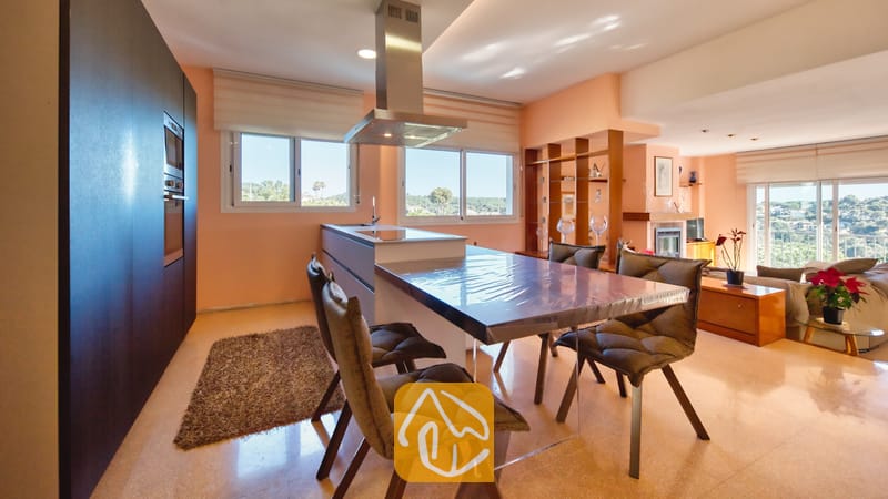 Vakantievilla's Costa Brava Spanje - Villa Valentina - Moderne keuken en eethoek met een glazen eettafel, gestoffeerde stoelen en een rvs-afzuigkap.