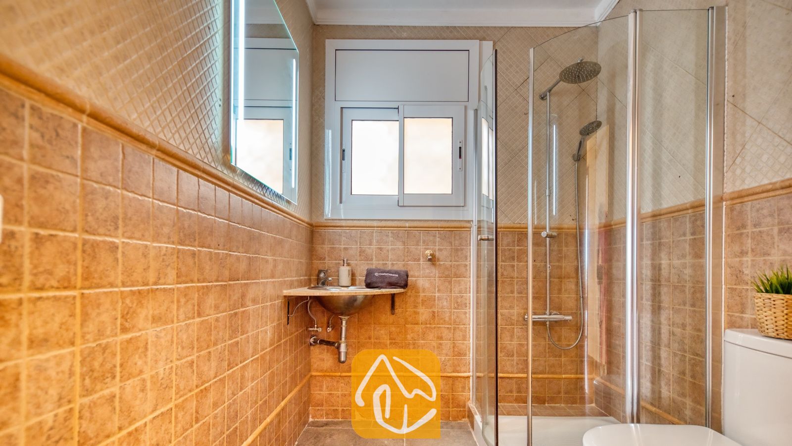 Vakantievilla's Costa Brava Spanje - Villa Donna - Badkamer voorzien van beige vierkante wandtegels, een glazen inloopdouche met twee douchekoppen en een wastafel.
