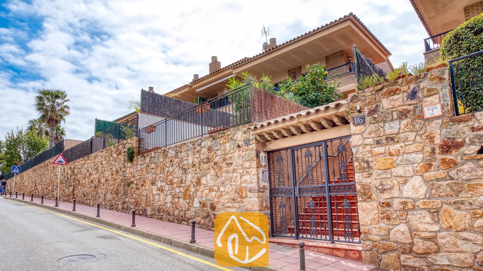 Vakantievilla's Costa Brava Spanje - Casa Costa - Buitenaanzicht van Casa Costa met een stenen keermuur, een donkere metalen poort en de gevel van het gebouw met meerdere verdiepingen en balkons.