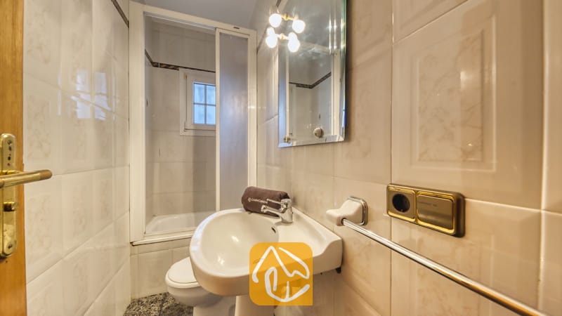 Vakantievilla's Costa Brava Spanje - Villa Rosa - Badkamer met een witte vrijstaande wastafel met chromen kraan, een wandspiegel met armatuur met meerdere lichtbronnen en betegelde muren.