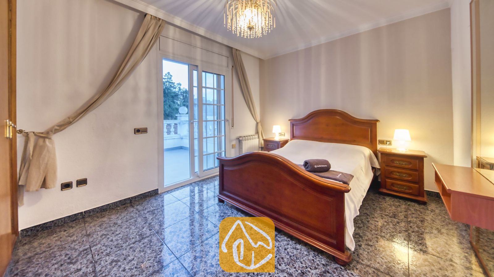 Vakantievilla's Costa Brava Spanje - Villa Rosa - Slaapkamer voorzien van een houten bedframe, tegelvloer en glazen schuifdeuren die toegang bieden tot een buitenbalkon.