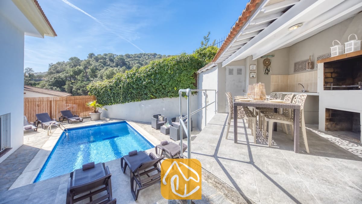 Vakantievilla's Costa Brava Spanje - Villa Rosa - De buitenzijde van Villa Rosa met een blauw zwembad, ligstoelen en een overdekt eitterras in de openlucht met een ingebouwde barbecue.