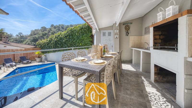 Vakantievilla's Costa Brava Spanje - Villa Rosa - Overdekt terras bij Villa Rosa met een eettafel buiten, een ingebouwde barbecue en uitzicht op het zwembad.