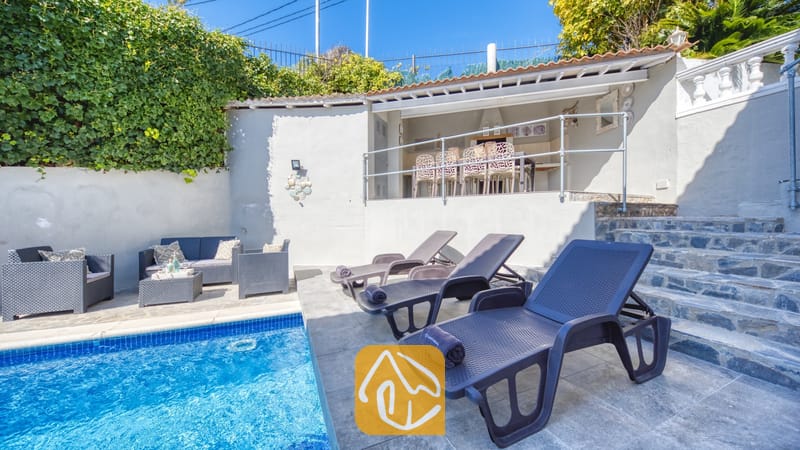 Vakantievilla's Costa Brava Spanje - Villa Rosa - Het privézwembadgedeelte van Villa Rosa, voorzien van donkergrijze kunststof ligbedden op een betegeld terras, een buitenloodsset met kussens en een overdekt terras erboven.