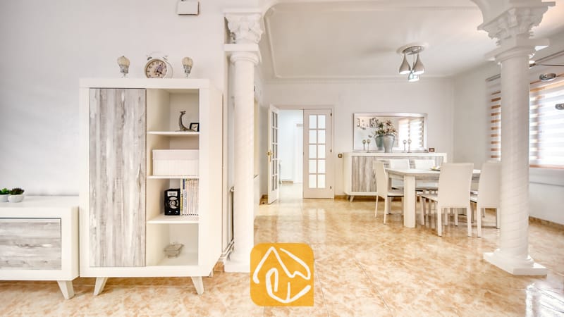 Vakantievilla's Costa Brava Spanje - Villa Sarai - Witte eethoek en woonkamer in Villa Sarai, voorzien van tegelvloeren, decoratieve zuilen en wittemeesubels met houten accenten.