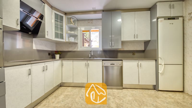 Vakantievilla's Costa Brava Spanje - Villa Sarai - Keuken met witte en grijze kasten, een roestvrijstalen vaatwasser en een raam boven de gootsteen.