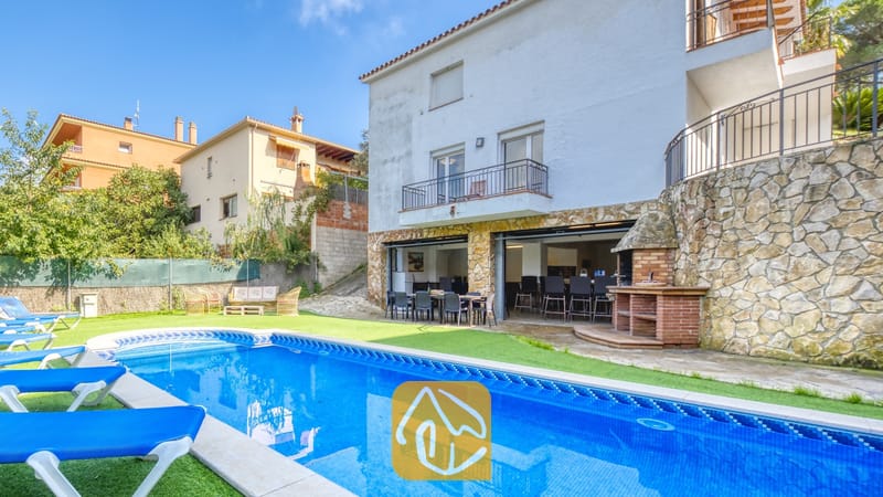 Vakantievilla's Costa Brava Spanje - Villa Nicky - Privézwembad met blauwe ligstoelen en een stenen terras bij Villa Nicky, met een witte, meerdere verdiepingen tellende buitenzijde, een buitenbarbecue en een open eetterras.