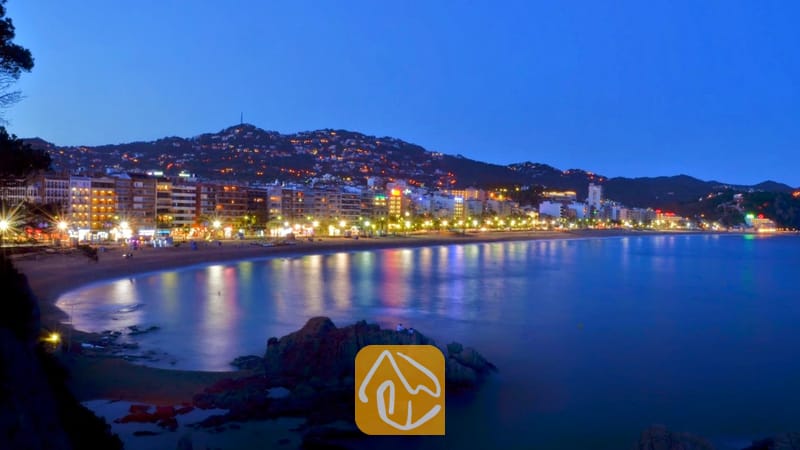Villas de vacances Costa Brava Espagne - Villa Pilar - La ville côtière et la plage de sable illuminées au crépuscule, avec leurs lumières colorées qui se reflètent sur l'eau calme, telles qu'aperçues depuis la Villa Pilar.