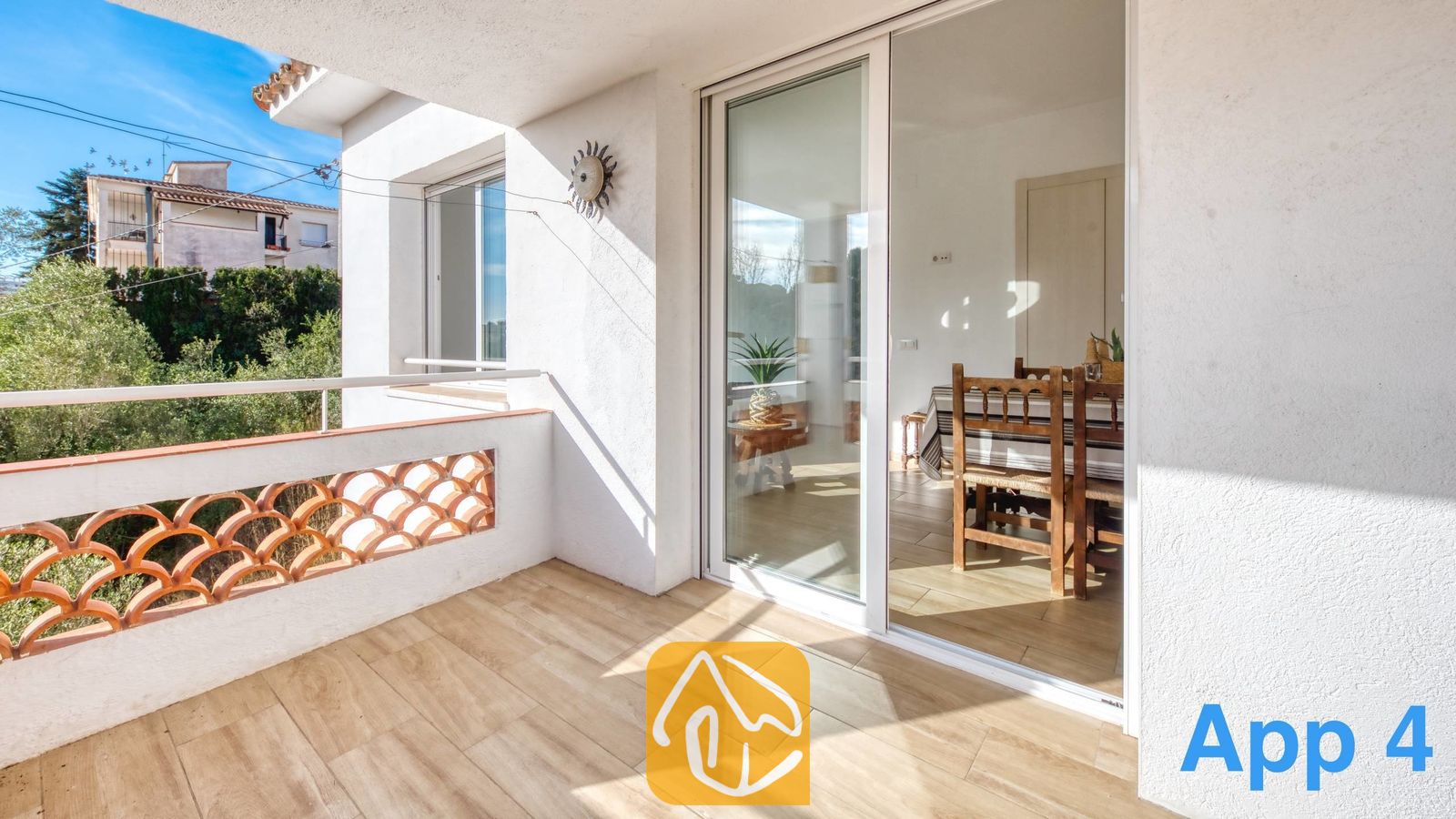 Vakantievilla's Costa Brava Spanje - Villa Pilar - Balkon met houten vlonders en een witte balustrade met uitzicht op de bomen, dat via schuifpuien van glas leidt naar het interieur van Villa Pilar.
