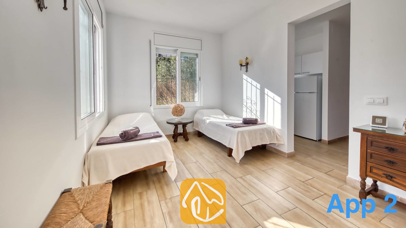 Vakantievilla's Costa Brava Spanje - Villa Pilar - Slaapkamer met twee eenpersoonsbedden opgemaakt met wit beddengoed, een nachtkastje van donker hout, tegelvloeren en witte muren.