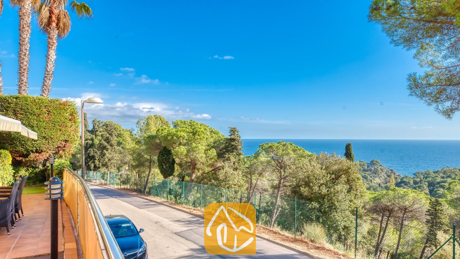 Vakantievilla's Costa Brava Spanje - Villa Santa Cristina - Kustpanorama vanaf Villa Santa Cristina met een geplaveide weg omzoomd door pijnbomen en een helder uitzicht op de blauwe zee in de verte.