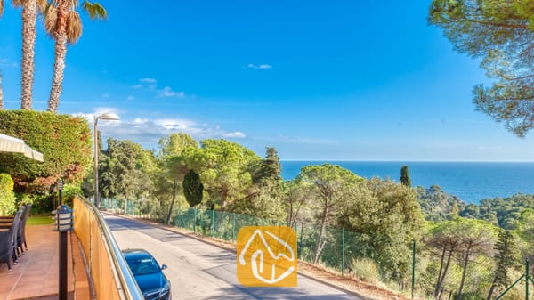 Vakantievilla's Costa Brava Spanje - Villa Santa Cristina - Kustpanorama vanaf Villa Santa Cristina met een geplaveide weg omzoomd door pijnbomen en een helder uitzicht op de blauwe zee in de verte.