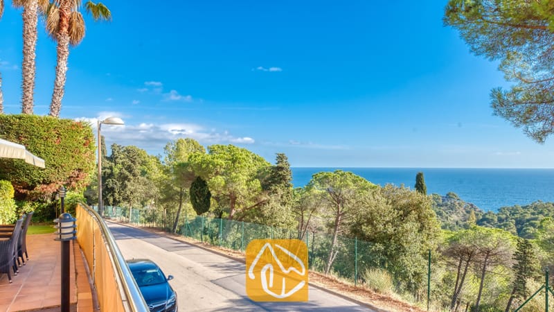 Vakantievilla's Costa Brava Spanje - Villa Santa Cristina - Kustpanorama vanaf Villa Santa Cristina met een geplaveide weg omzoomd door pijnbomen en een helder uitzicht op de blauwe zee in de verte.