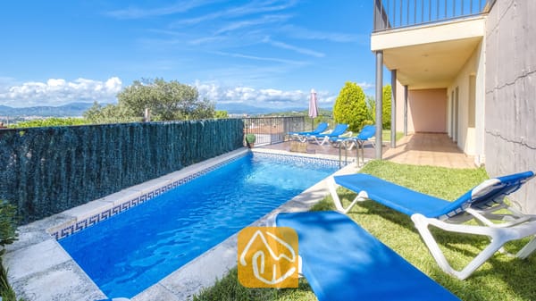 Vakantievilla's Costa Brava Spanje - Villa Mauri - Privézwembad bij Villa Mauri met helderblauw water, een betegelde rand en blauwe ligstoelen op het gras.