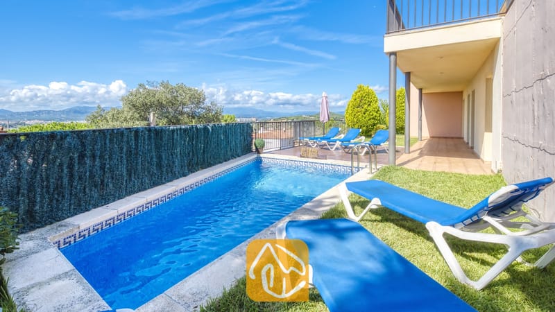Vakantievilla's Costa Brava Spanje - Villa Mauri - Privézwembad bij Villa Mauri met helderblauw water, een betegelde rand en blauwe ligstoelen op het gras.