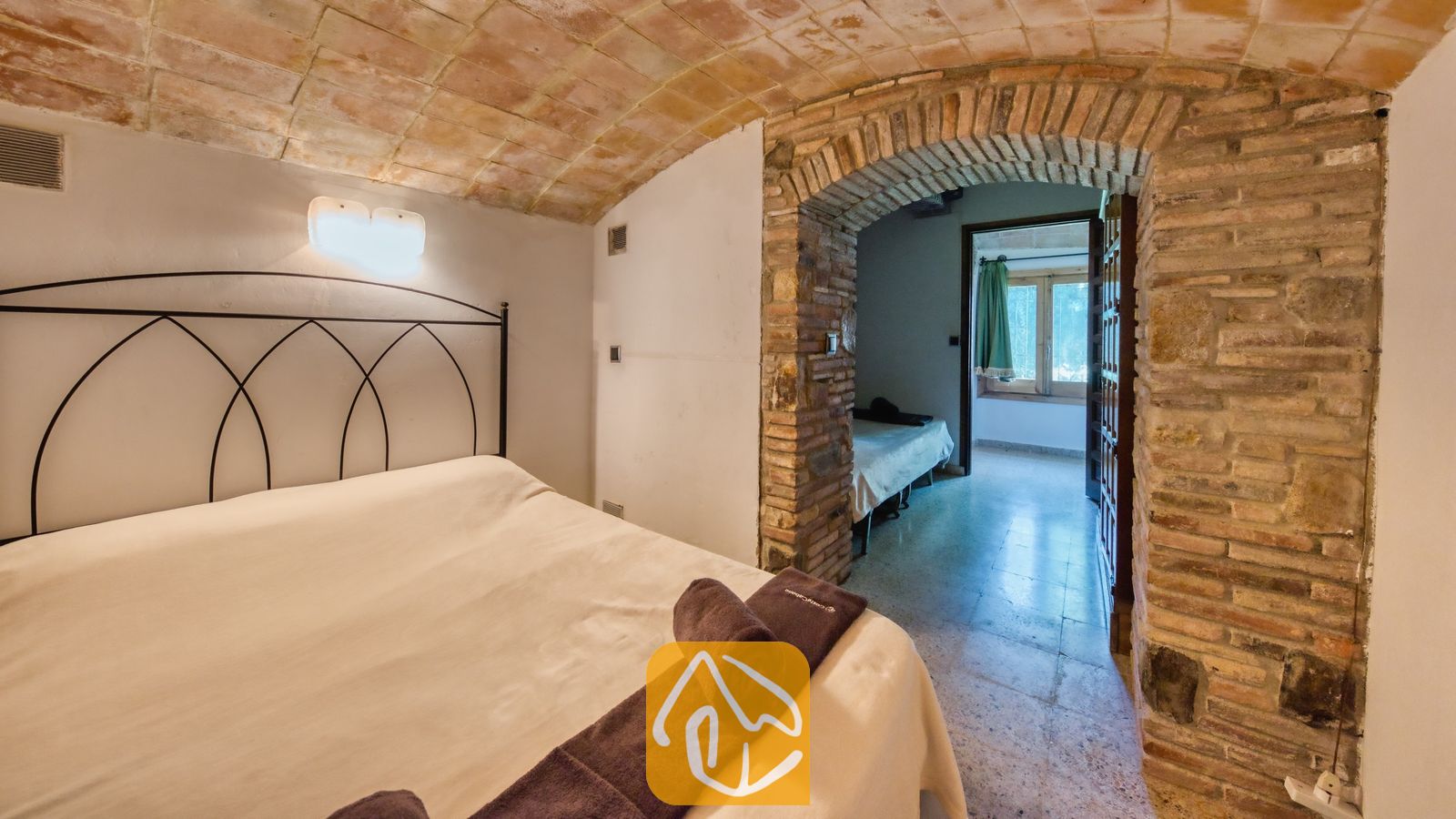 Vakantievilla's Costa Brava Countryside Spanje - Villa Can Bernardi - Slaapkamer met een traditioneel stenen plafond en een gebogen stenen doorgang naar een aaneengesloten kamer in Villa Can Bernardi