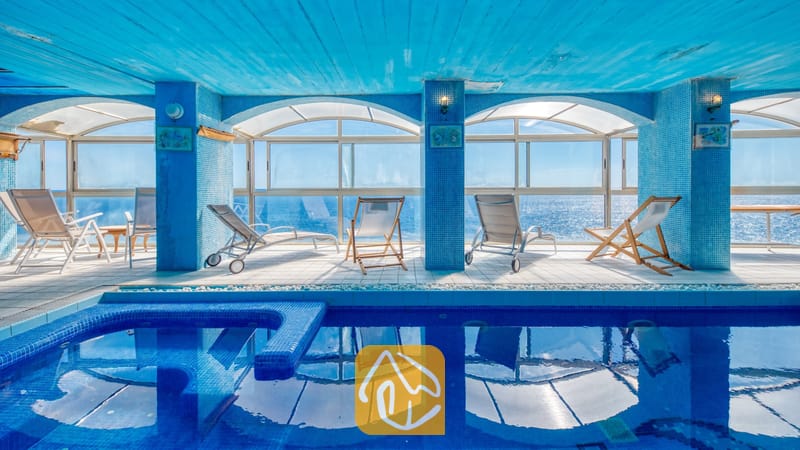 Villas de vacances Costa Brava Espagne - Villa Infinity - Piscine intérieure et chaises longues à la Villa Infinity, dotée de colonnes en mosaïque bleue, de fenêtres en arc et d'une vue directe sur la mer.