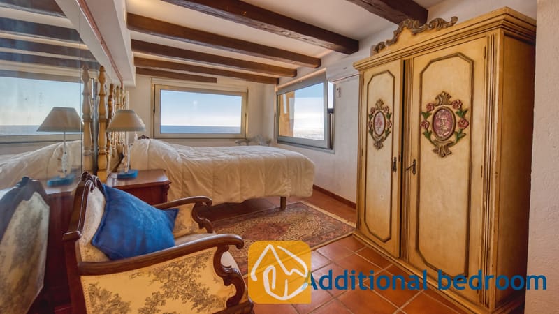 Villas de vacances Costa Brava Espagne - Villa Infinity - Chambre à coucher avec poutres en bois au plafond, grande armoire, sol carrelé et deux fenêtres offrant une vue sur la mer.