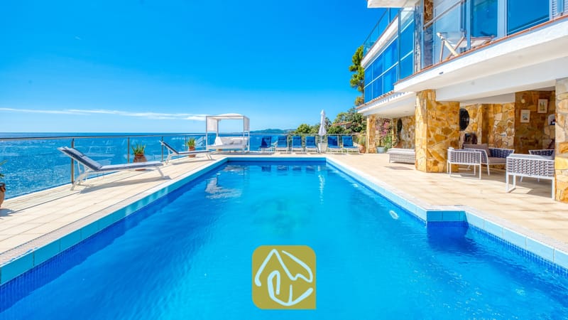 Vakantievilla's Costa Brava Spanje - Villa Infinity - Rechthoekig zwembad bij Villa Infinity met blauw water, omringd door ligstoelen en een stenen terras met uitzicht op zee.