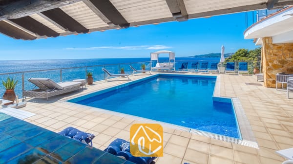 Vakantievilla's Costa Brava Spanje - Villa Infinity - Villa Infinity terras met een rechthoekig blauw zwembad, glazen balustrade en meerdere ligstoelen met uitzicht op zee.