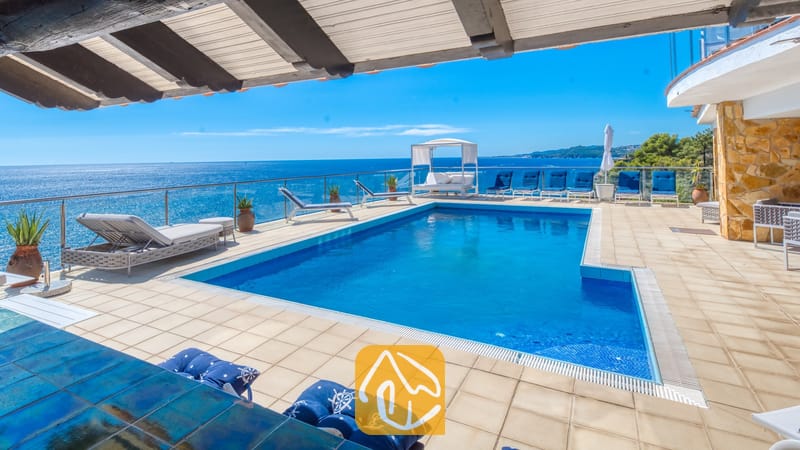 Vakantievilla's Costa Brava Spanje - Villa Infinity - Villa Infinity terras met een rechthoekig blauw zwembad, glazen balustrade en meerdere ligstoelen met uitzicht op zee.